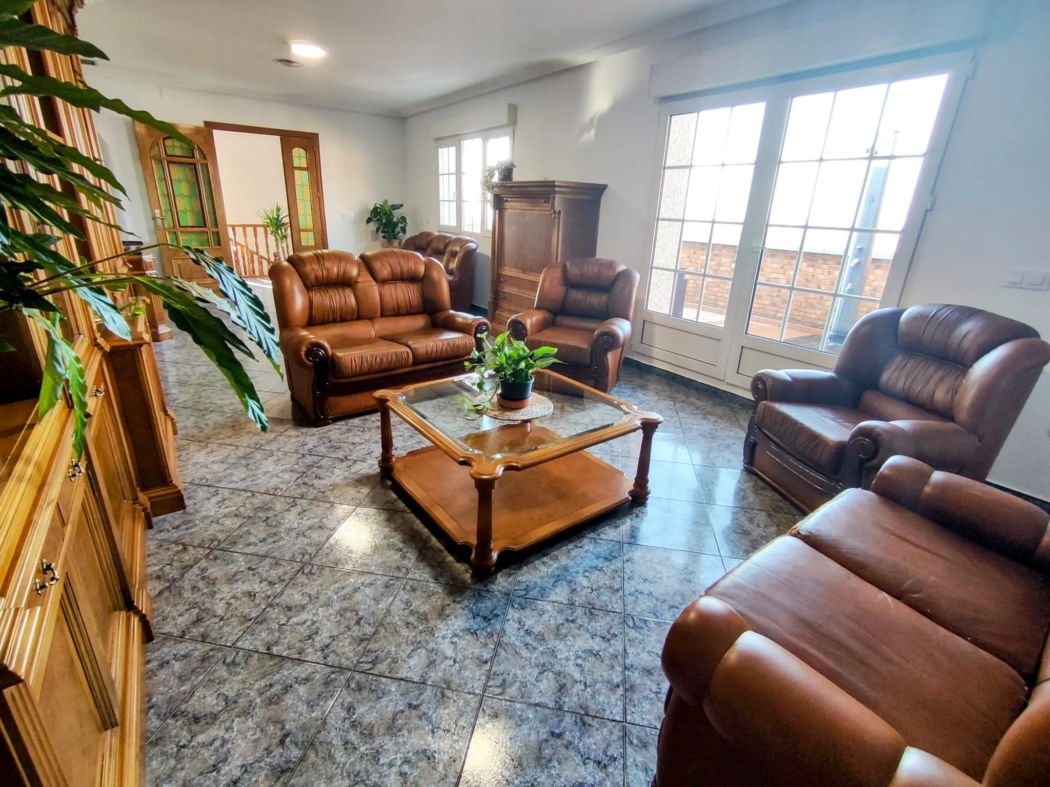 Elegante y espacioso salón con sillones de cuero y terraza con vistas