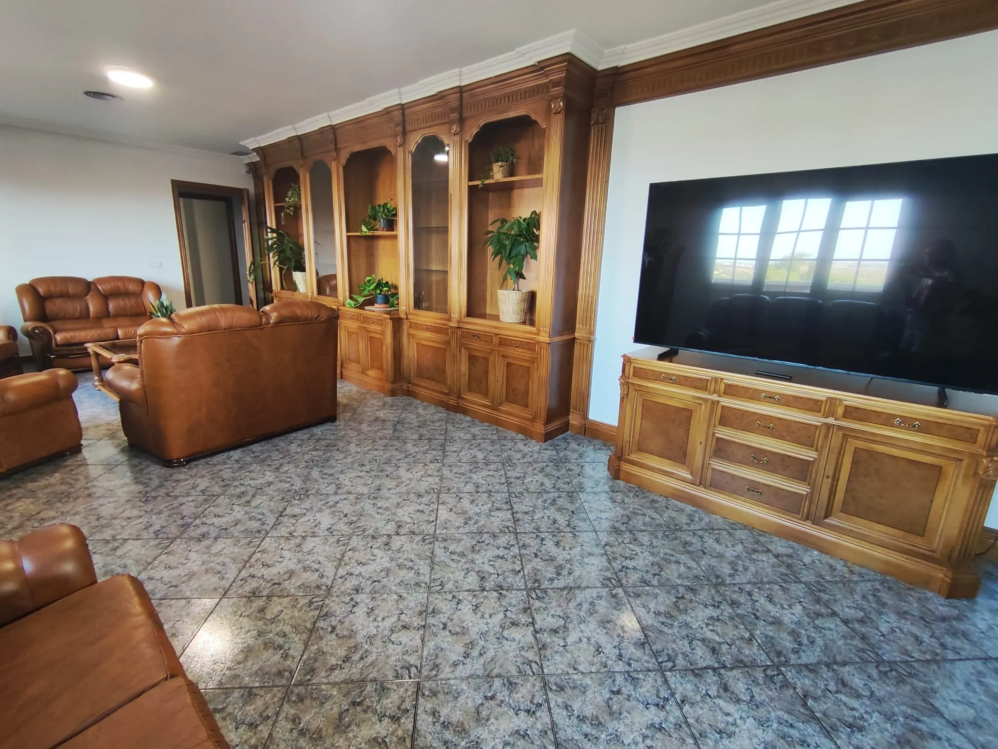 Elegante y espacioso salón con sillones de cuero, TV de 75