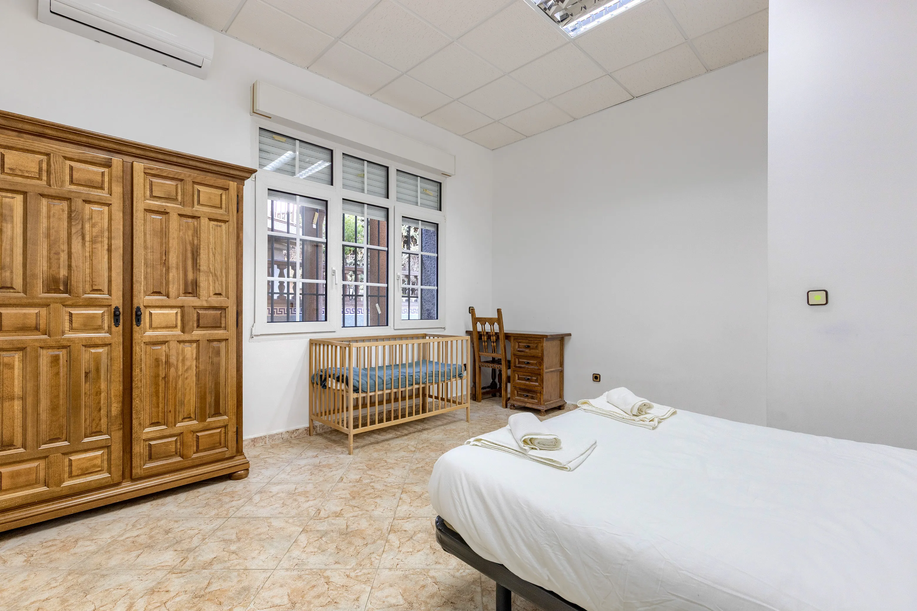 Habitación con cama doble, mesa de trabajo, AC y cuna