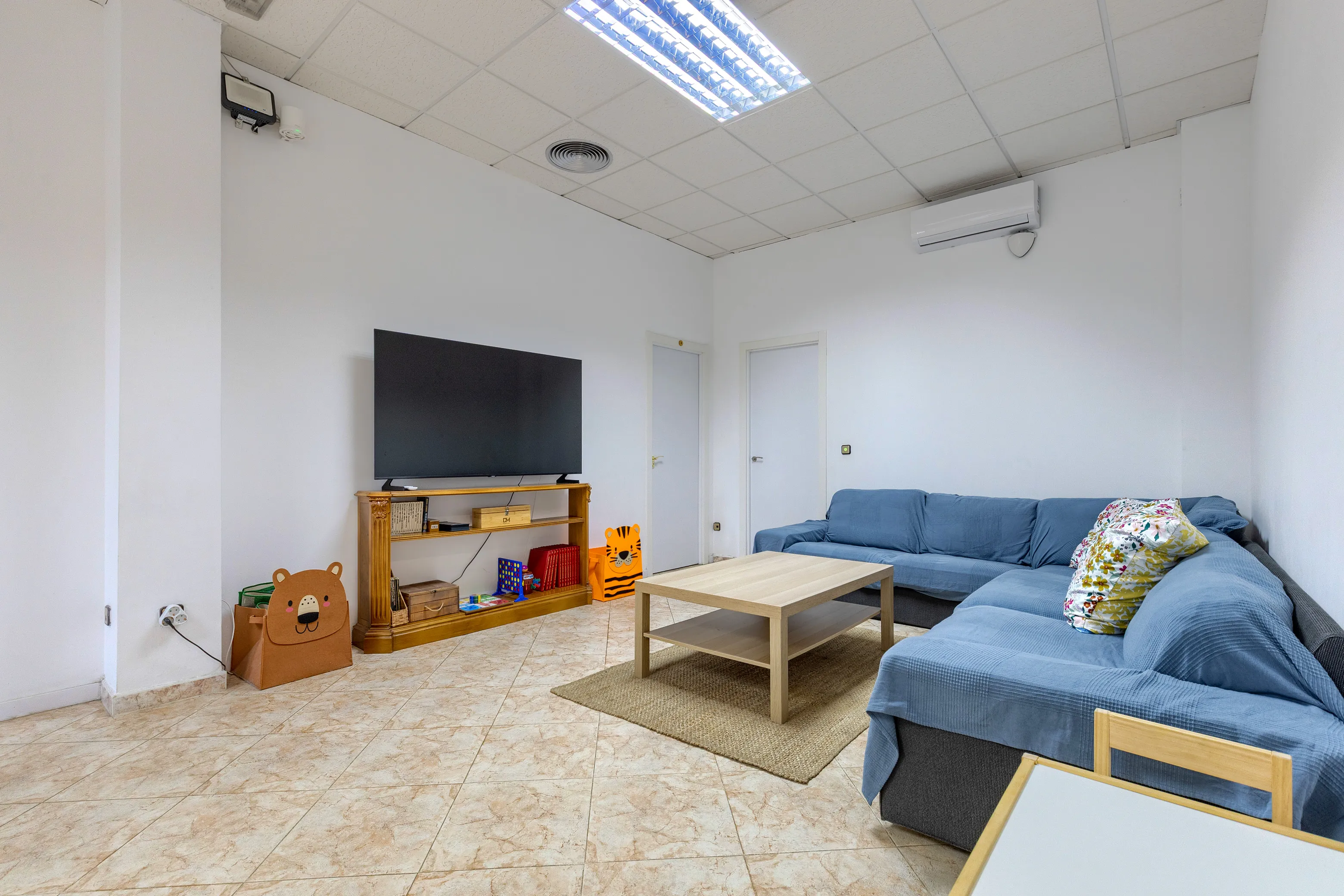 Salón con amplios sofás, Smart TV de 65, juegos de mesa y espacio para niños